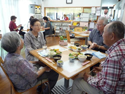 高齢者の方々が四人ずつテーブルを囲み、食事をされている写真